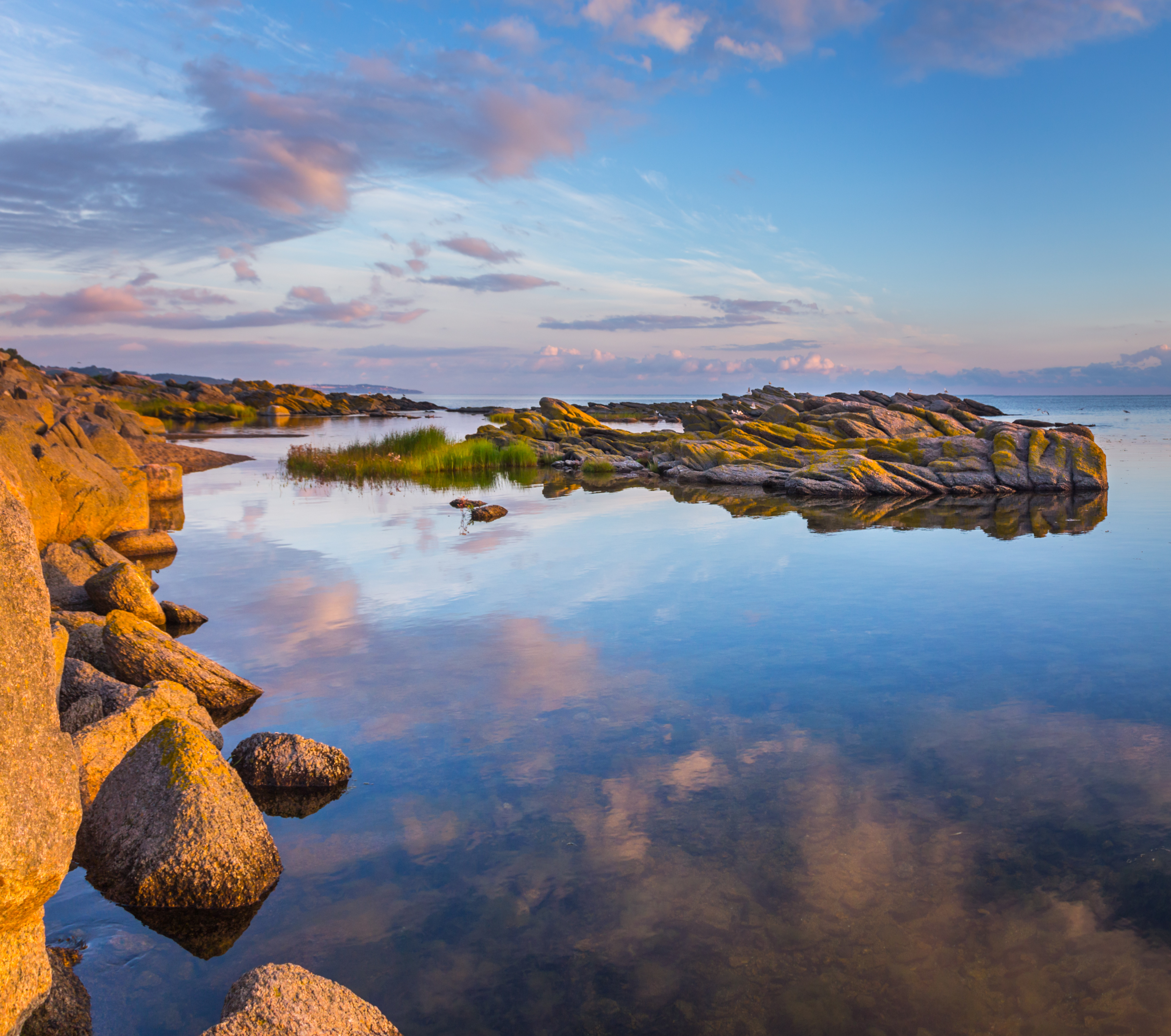 Skyerne spejler sig i havet med klipper